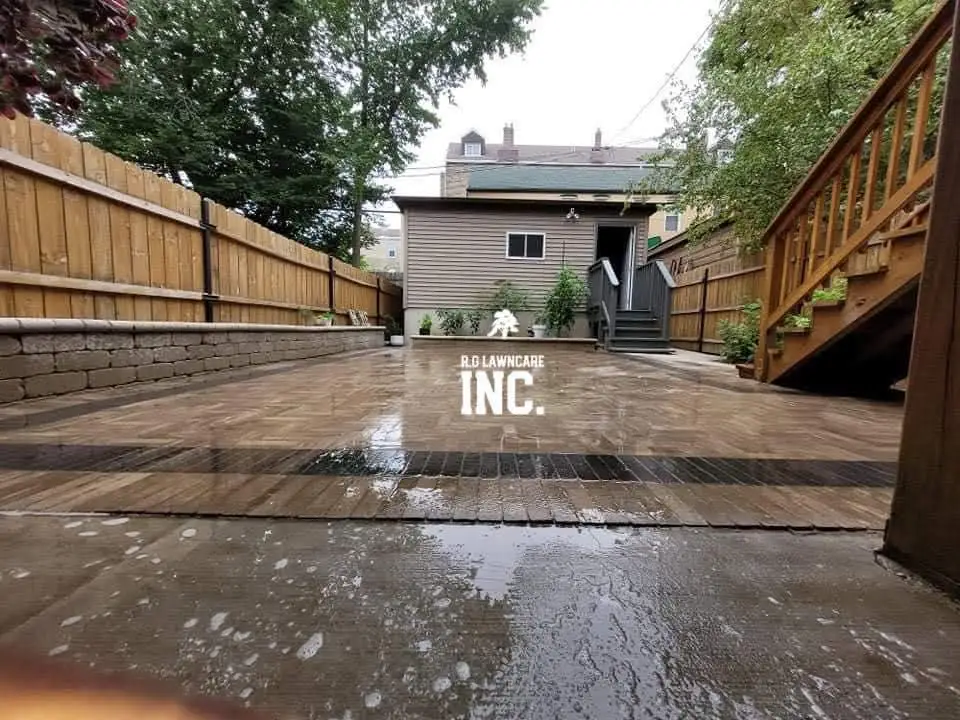 Large multi-tone paver patio with block seat wall in a city backyard